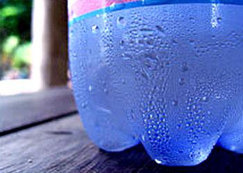 Water vapour condenses into a liquid after making contact with the surface of a cold bottle.